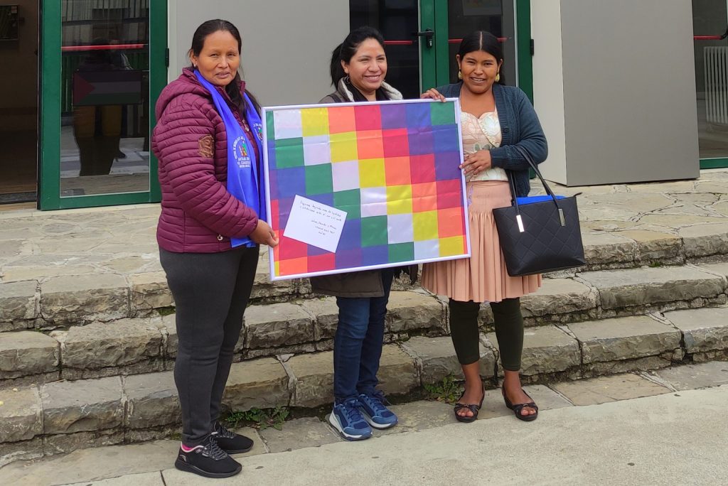 Salomé, Marcia y Eduarda sostienen la bandera wiphala.